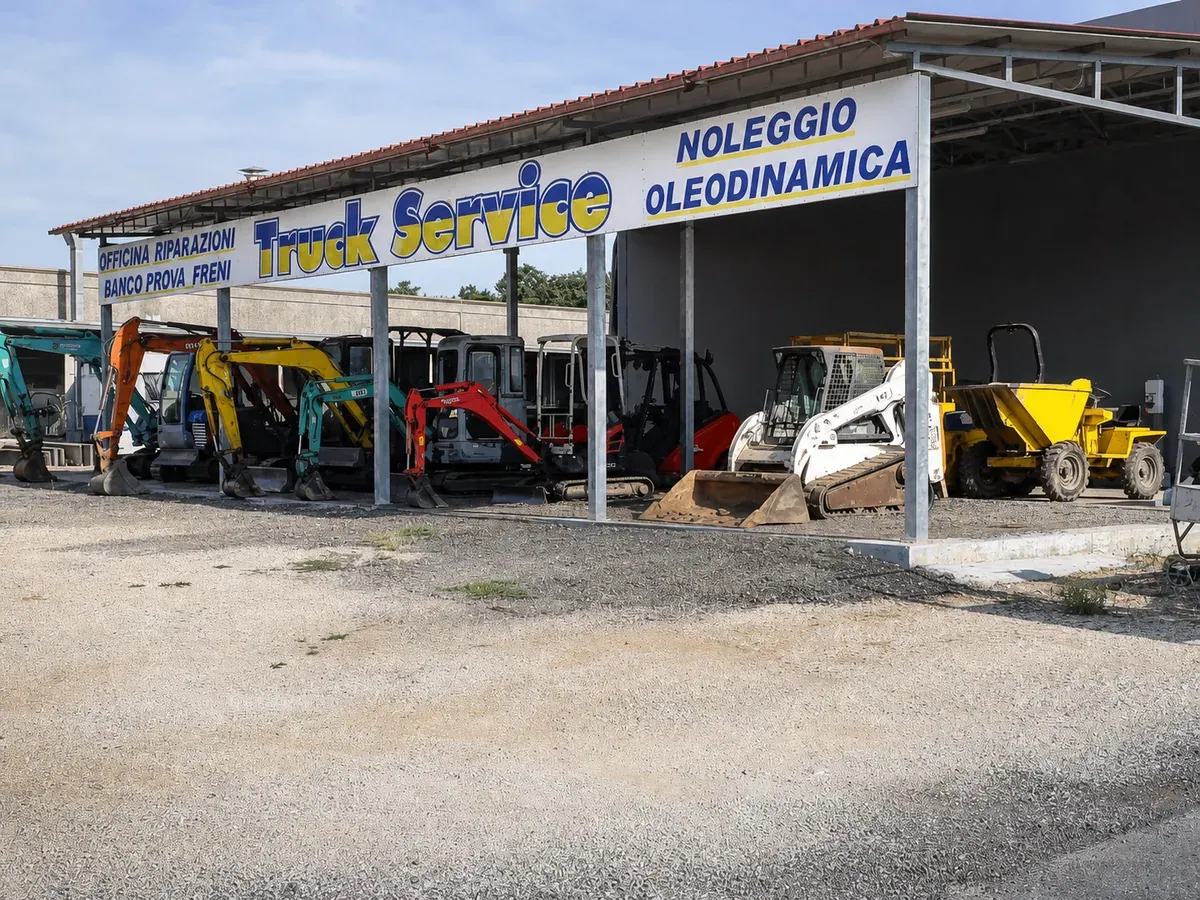 La tettoia del noleggio con miniescavatori, minipala e dumper in fila sotto l'insegna Truck Service
